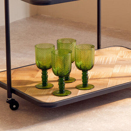 Two-tiered serving cart with green glasses and a pitcher on a neutral background