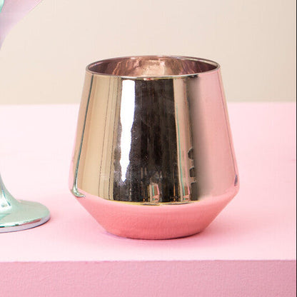 Two metallic wine glasses, one silver and one rose gold, on a pink surface with a beige background.