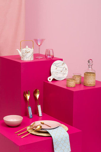 Table setting with pink and gold tableware on a pink background