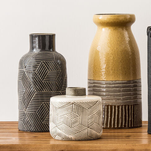Set of five ceramic vases with geometric patterns on a wooden surface.
