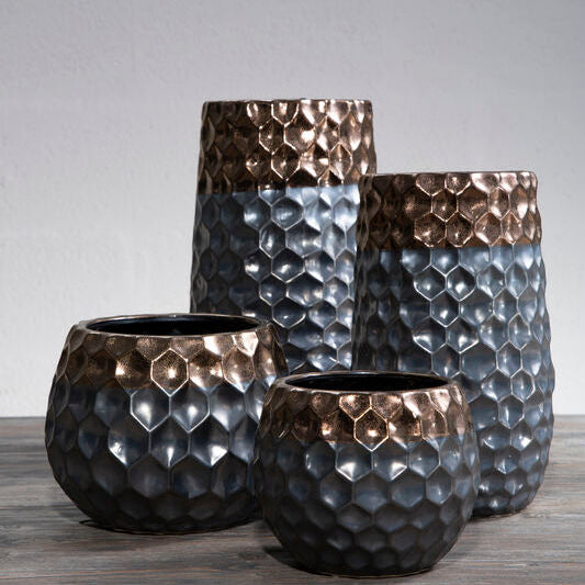 Set of four textured vases on a wooden surface with a gray background