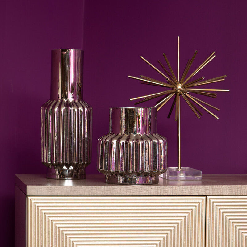 Decorative vases and a star-shaped lamp on a cabinet against a purple wall
