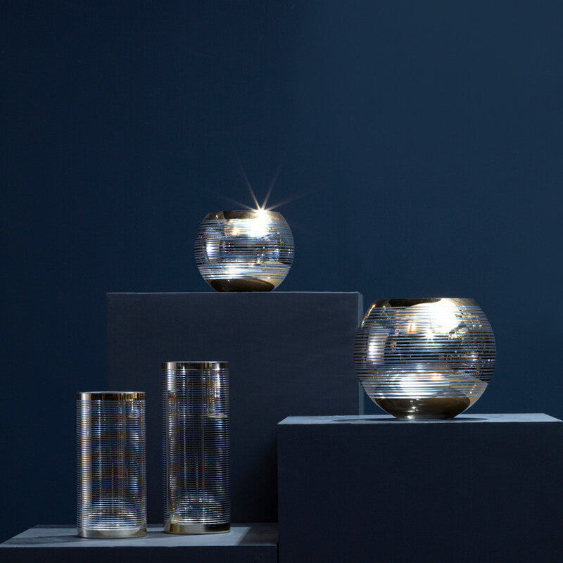 Set of metallic glass containers on a dark background