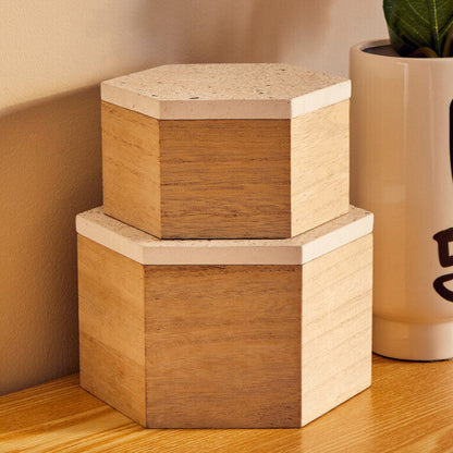 Two wooden hexagonal boxes and a vase with pink flowers on a wooden surface.