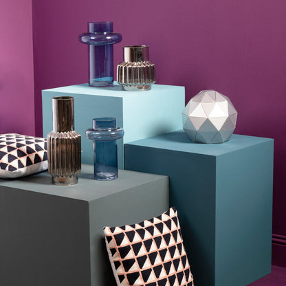 Decorative objects on colorful geometric shelves against a purple wall.