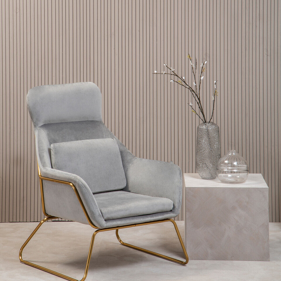 Gray armchair with gold legs in a minimalistic room with a striped wall and small table.