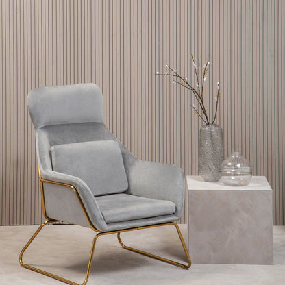 Gray armchair with gold legs in a minimalistic room with a striped wall and small table.