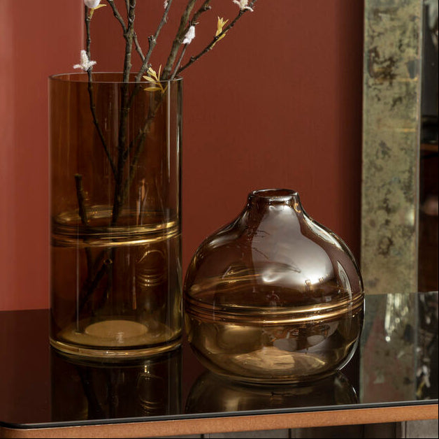 Two glass vases on a reflective surface with a red wall in the background