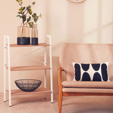 Living room with a shelf, plant, clock, and sofa with a pillow.