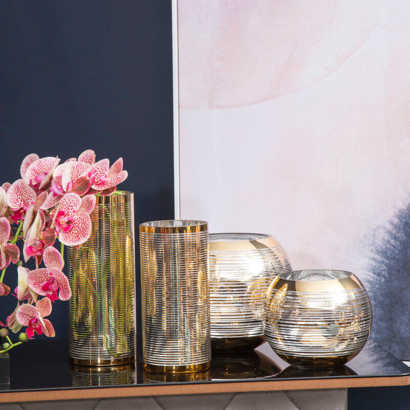 Decorative table with gold and silver vases against a wall with abstract art