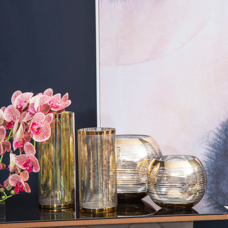 Decorative table with gold and silver vases against a wall with abstract art