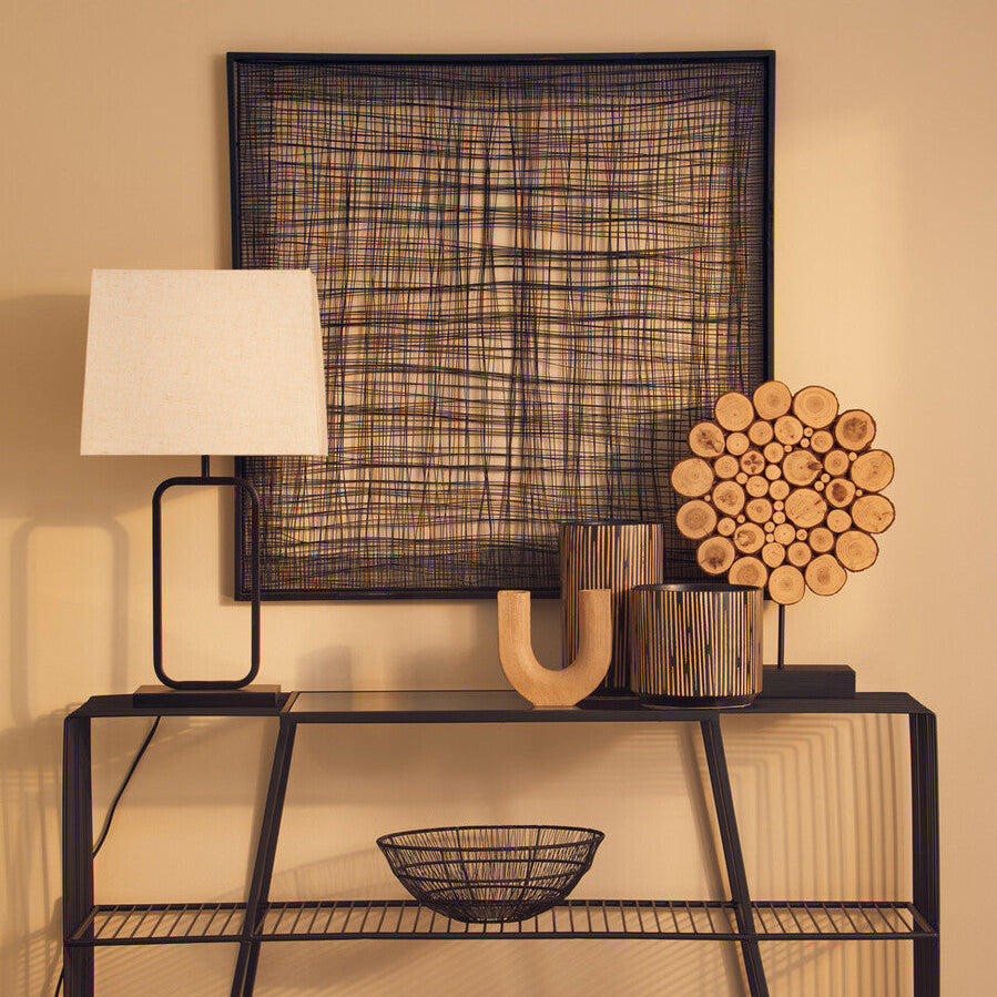 Modern black metal console table with decorative items against a beige wall.