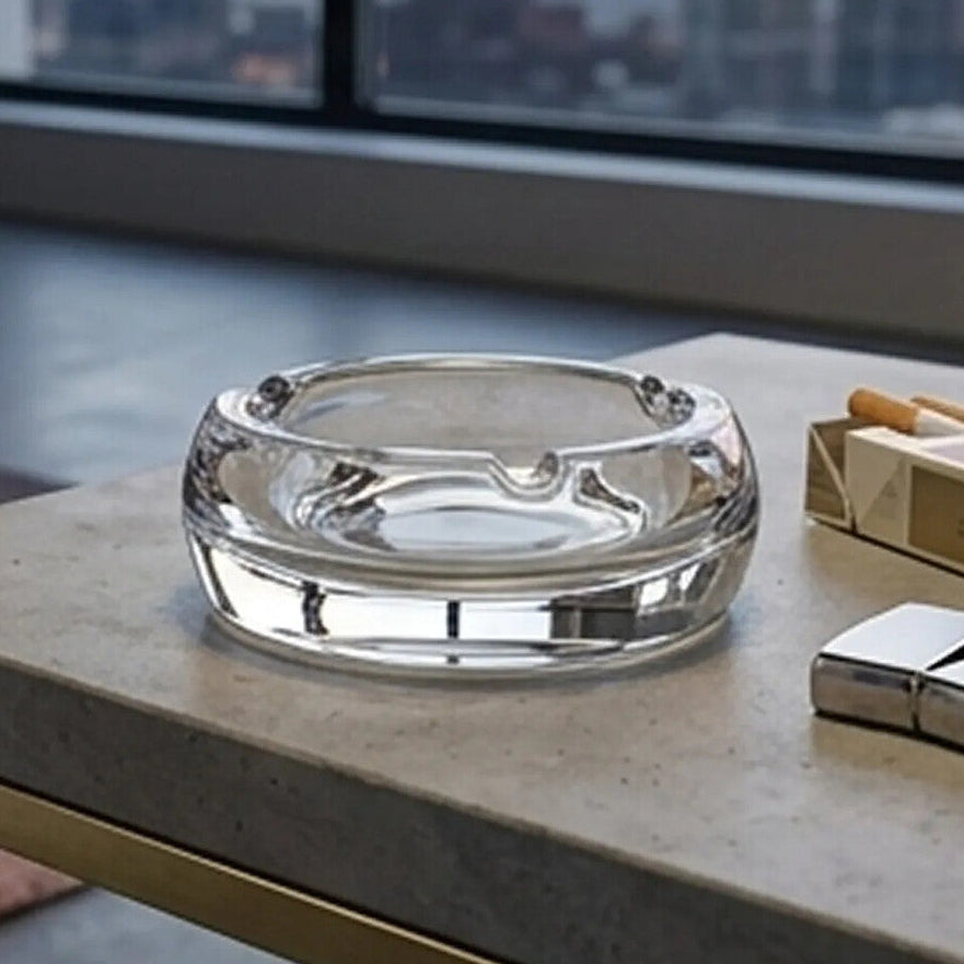Clear crystal ashtray on a table with a cityscape view in the background