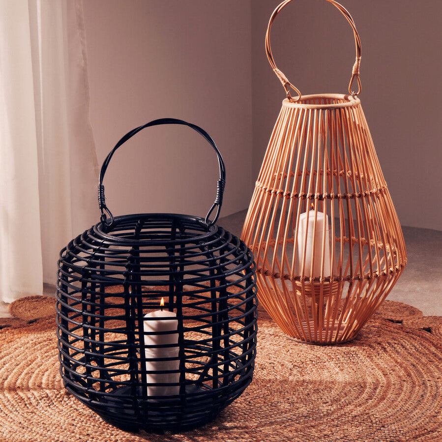 Two woven lanterns, one black and one copper, on a textured surface with a neutral background.