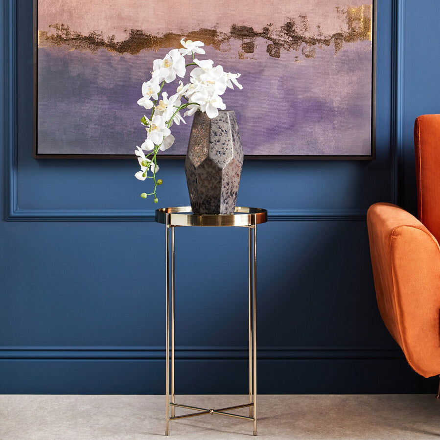 Decorative interior setting with a vase of white flowers on a small table against a blue wall.