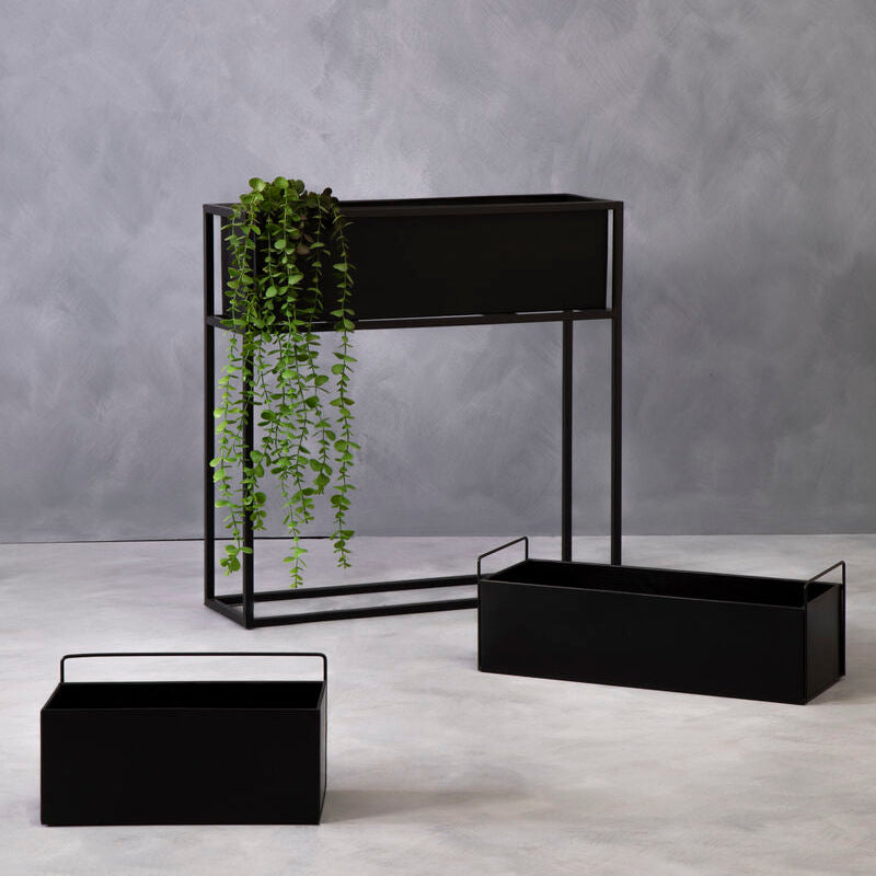 Set of black metal planters with a gray concrete wall background