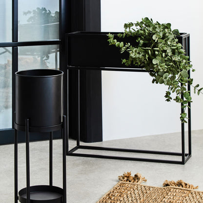 Black metal plant stand with a green plant indoors