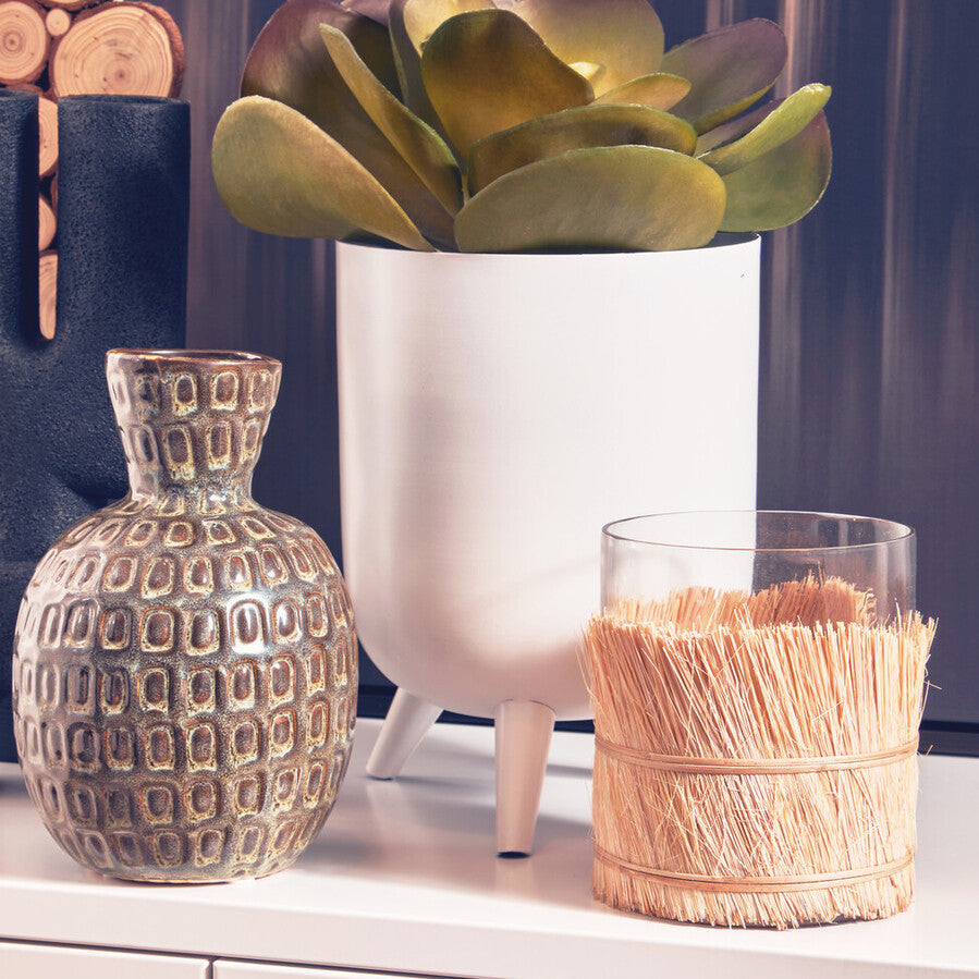 Decorative items including a textured vase, white pot with succulent, and woven basket on a surface.