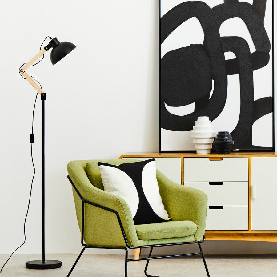 Modern interior with a green armchair, black floor lamp, and abstract art on the wall.