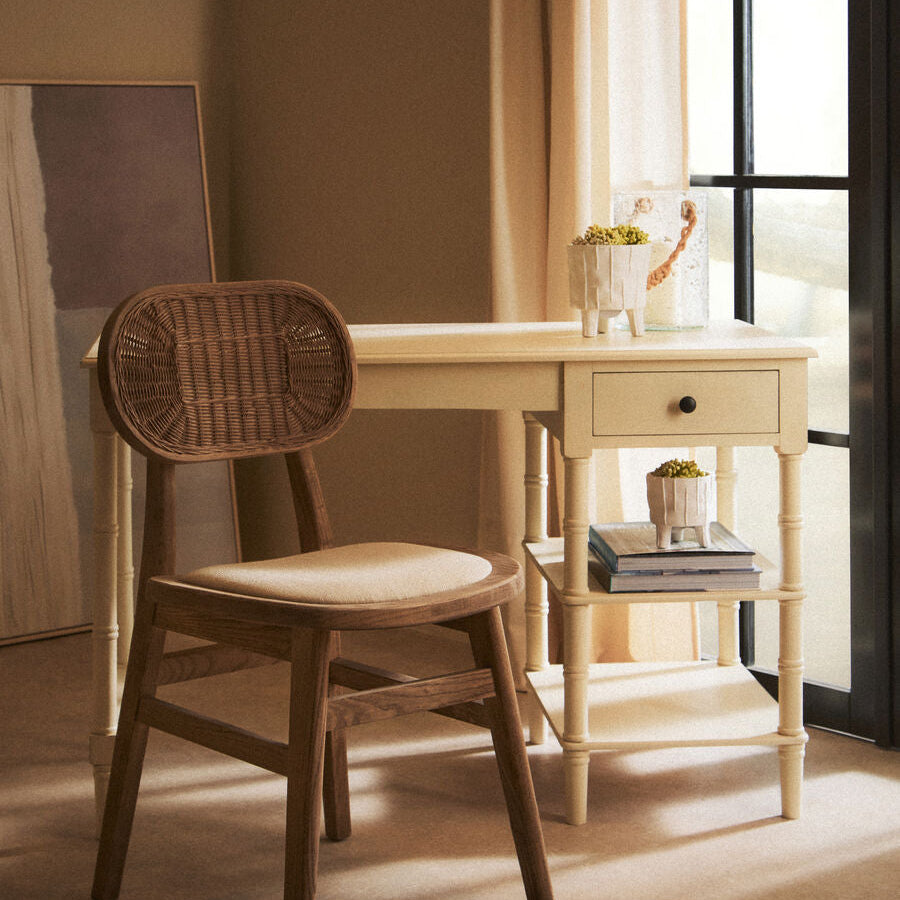 Wooden chair with wicker backrest in front of a light-colored desk.