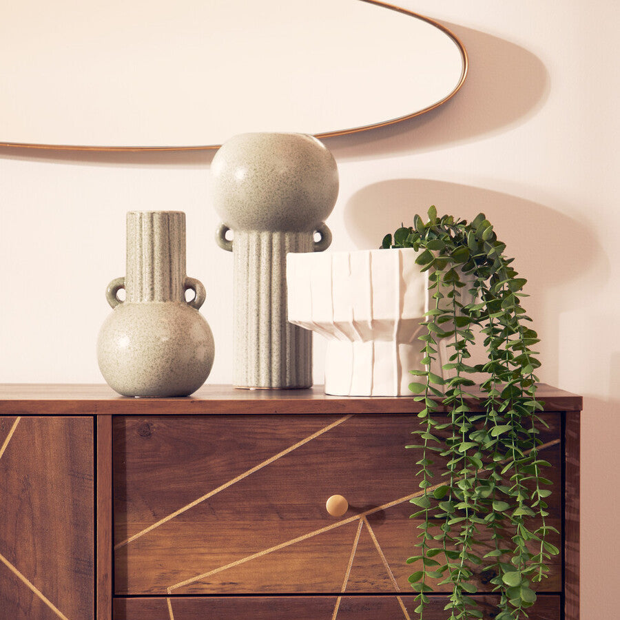 Wooden dresser with geometric design, decorative vases, and a plant in a modern interior setting.