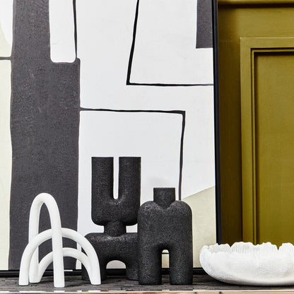 Decorative black and white sculptures on a wooden surface with abstract art in the background.