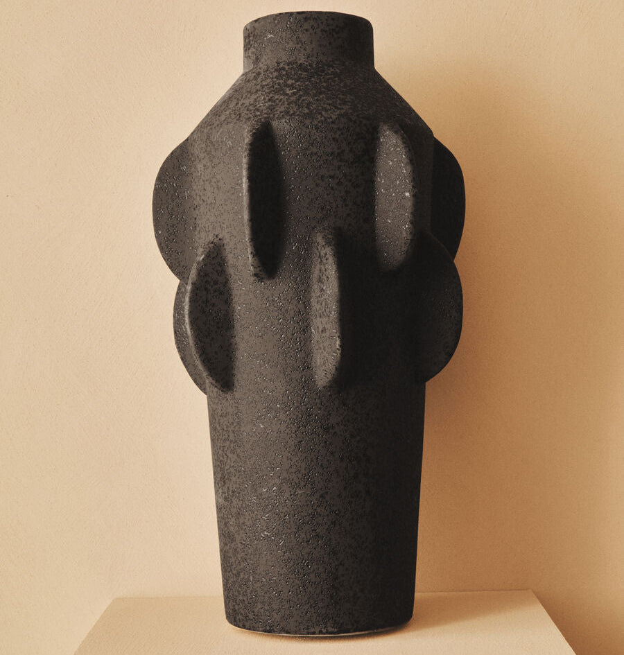 Black abstract vase on a beige pedestal against a beige background