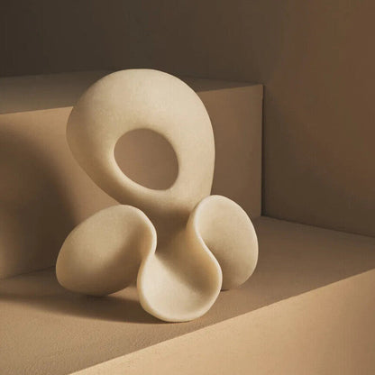 Abstract white sculpture on a beige surface with a dark background
