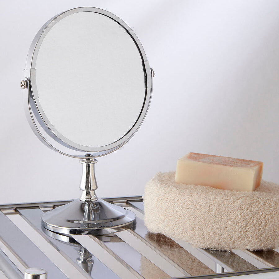 Makeup mirror on a glass surface with a bar of soap and washcloth in the background