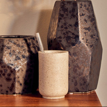 Three decorative vases on a wooden surface with a neutral background