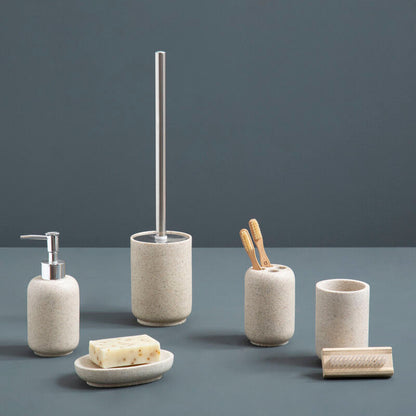 Set of bathroom accessories including a soap dispenser, toilet brush holder, and other items on a gray surface with a dark gray background.