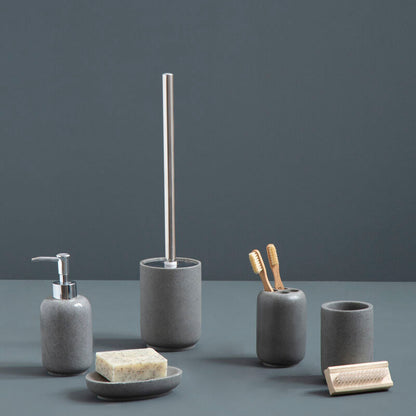 Set of gray bathroom accessories including a soap dispenser, brush holder, and cups on a dark surface with a dark background.
