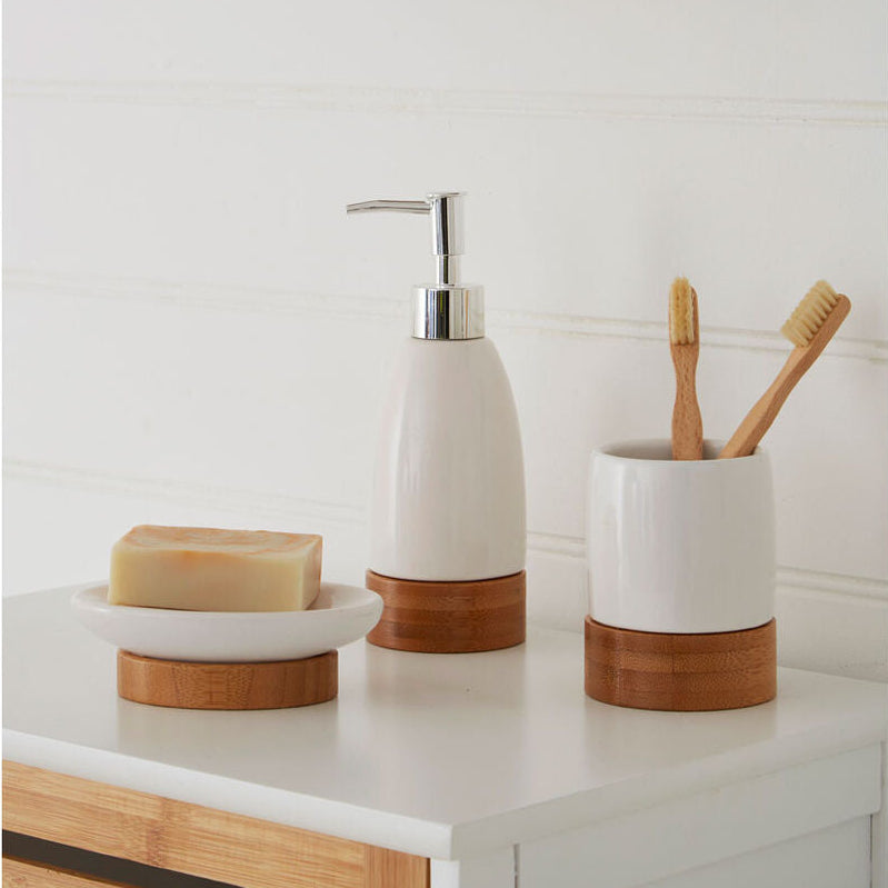 Bathroom counter with wooden and ceramic accessories including a soap dispenser, toothbrush holder, and soap dish.