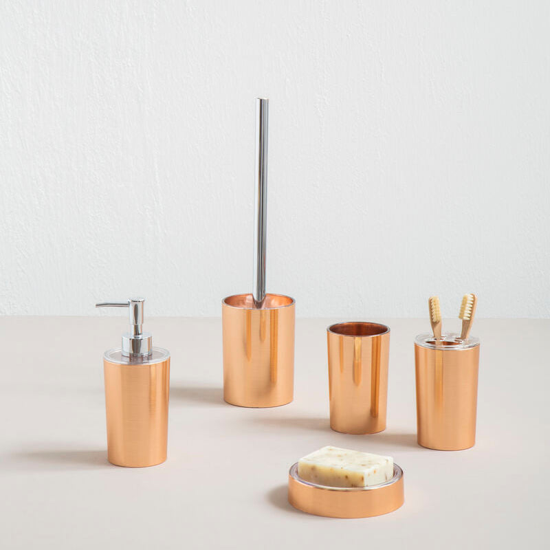 Set of gold bathroom accessories including a dispenser, scrubber, and containers on a light background