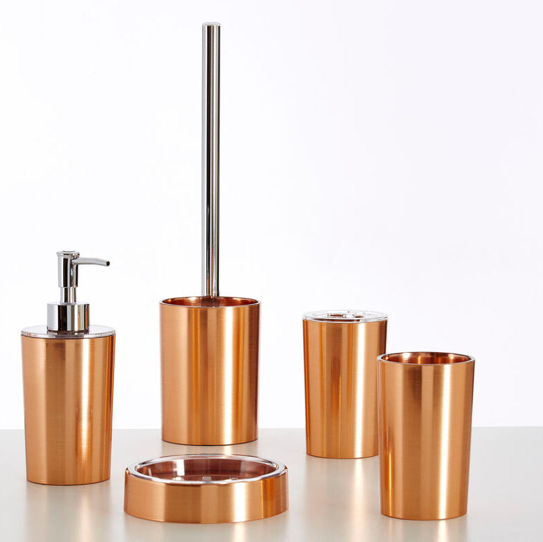 Set of bronze bathroom accessories including a dispenser, brush holder, and cups on a white background