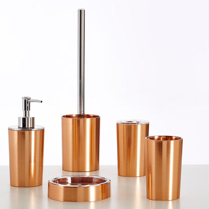 Set of bronze bathroom accessories including a dispenser, brush holder, and cups on a white background