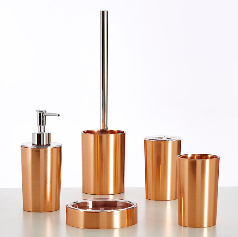Set of bronze bathroom accessories including a dispenser, brush holder, and cups on a white background