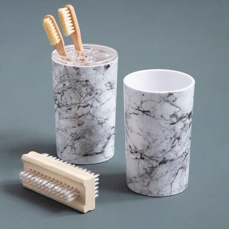 Marble-patterned toothbrush holder with toothbrushes and a scrubber on a gray background