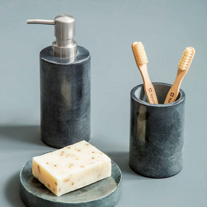 Marble bathroom set with soap dispenser, toothbrush holder, and soap on a gray surface.