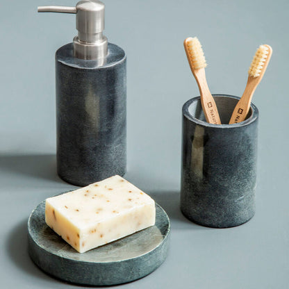 Marble bathroom set with soap dispenser, toothbrush holder, and soap on a gray surface.