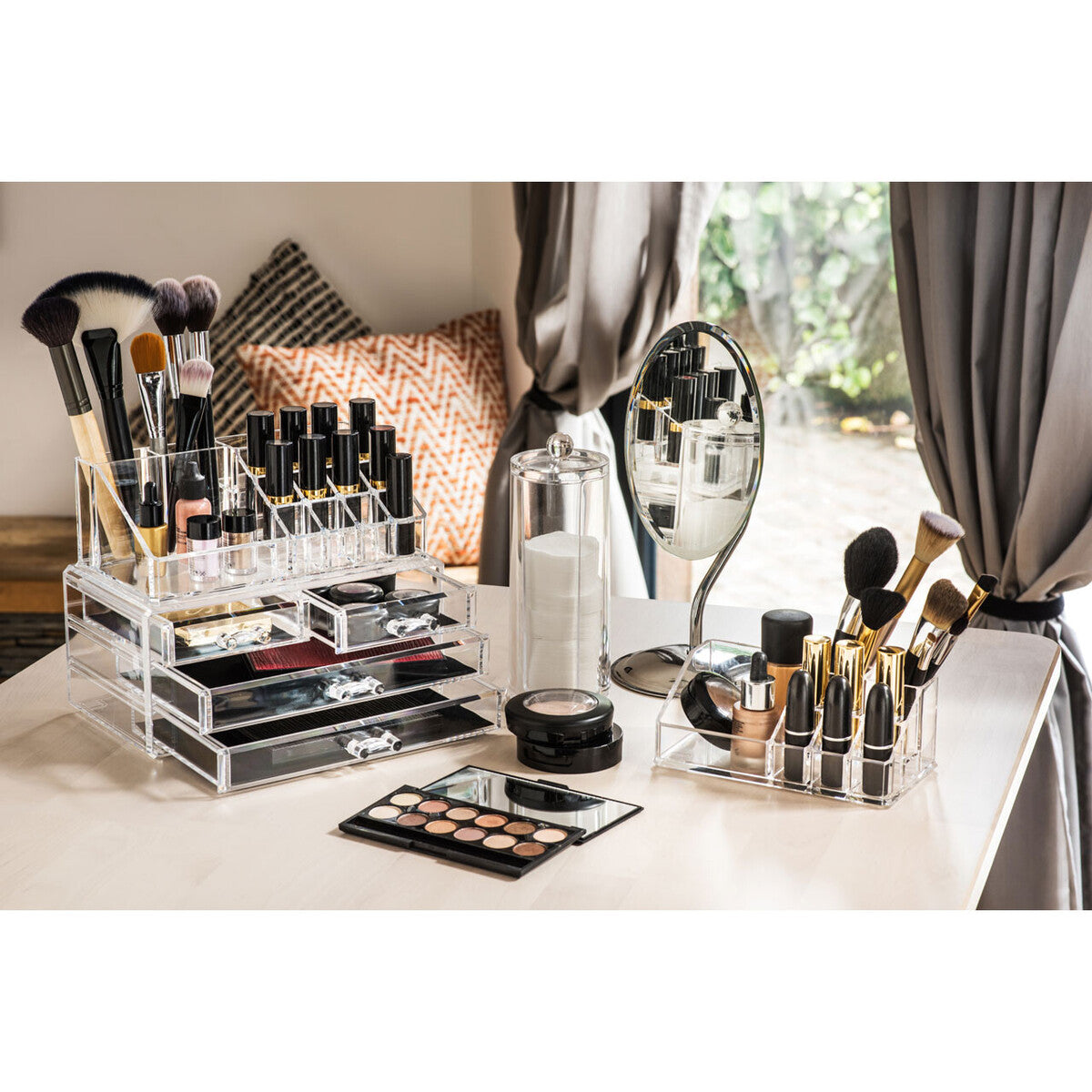 Makeup brushes, products, and a mirror on a vanity table.