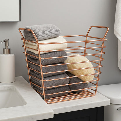 Bronze wire basket on a bathroom counter holding towels and a sponge.