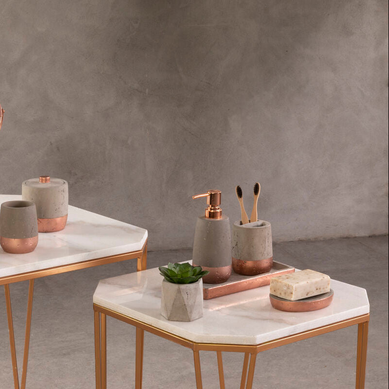 Bathroom accessories including a mirror, cups, and soap dispenser on marble surfaces with a neutral background.