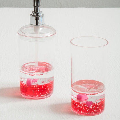 Clear soap dispenser with pink liquid on a white surface