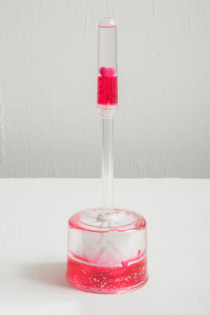 Clear bottle with pink liquid and cotton balls on a white background