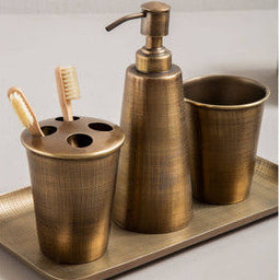 Bronze bathroom accessory set with dispenser, cups, and toothbrush holder on a tray.
