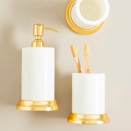 Bathroom accessories set with gold fixtures and white containers on a beige wall.