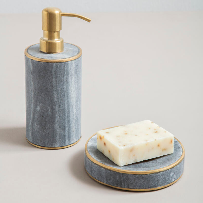 Soap dispenser and soap dish set with marble-like finish and gold accents on a neutral background