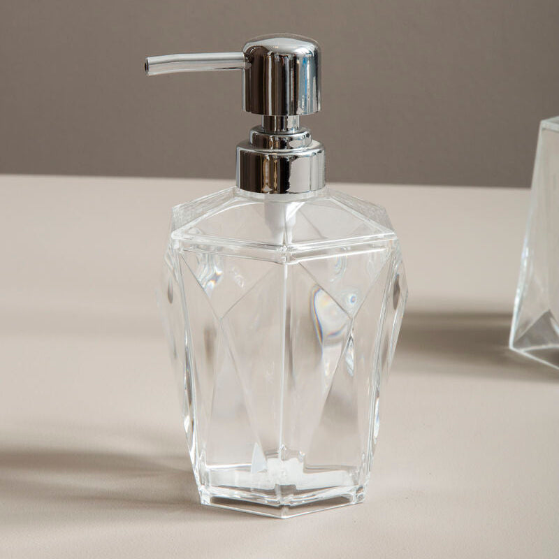 Clear glass soap dispenser with silver pump on a neutral background