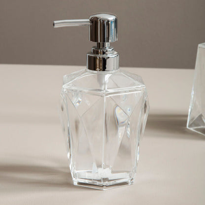 Clear glass soap dispenser with silver pump on a neutral background
